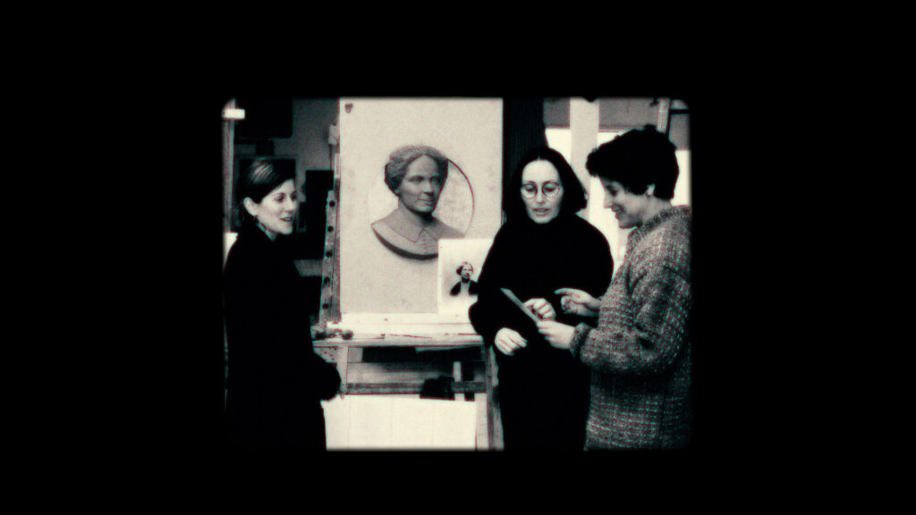 Screen grab of a few museum docents speaking together in front of a work of art.