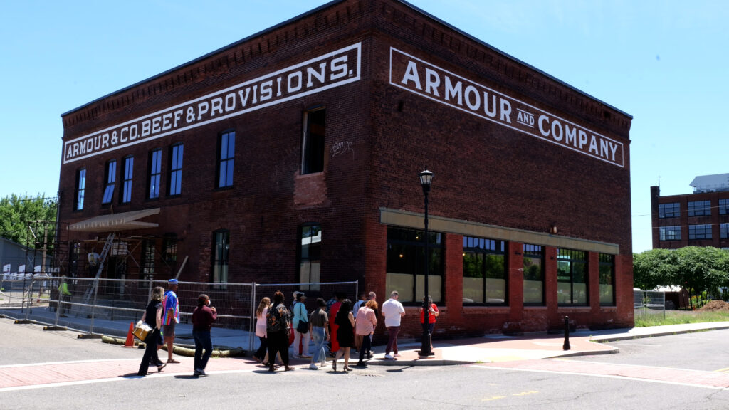 A group of Mass Humanities grantees walks in front of the organization's future headquarters, located at 130 Race Street in Holyoke.