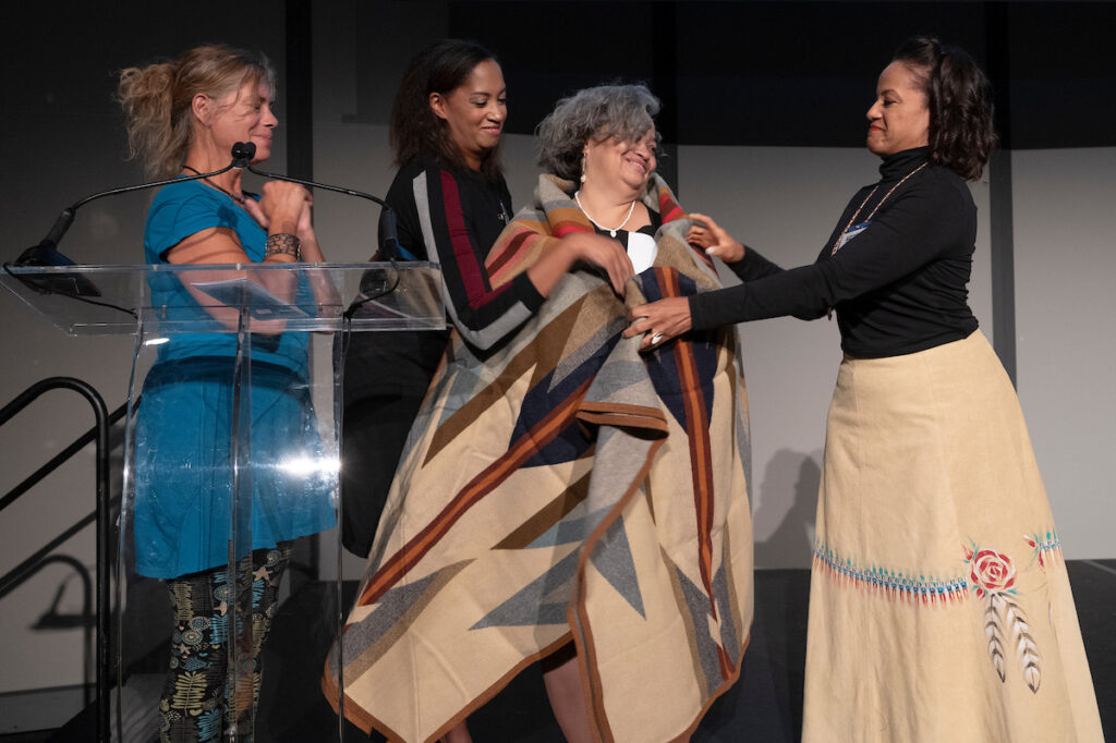 Cheryll Toney Holley is presented with a blanket by members of the Hassanamisco Nipmuc Band Council.