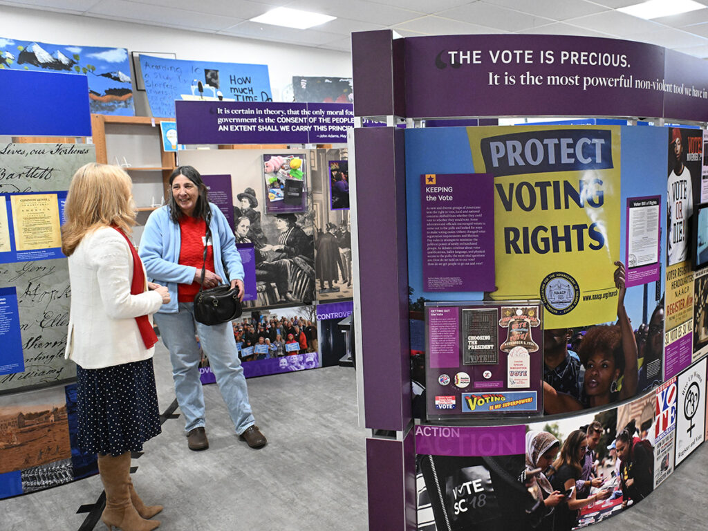 Two women view the Voices and Votes exhibit at Mohawk Trail Regional School.